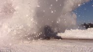 The person videoing the action is showered with a huge snow cloud as the train crashes past